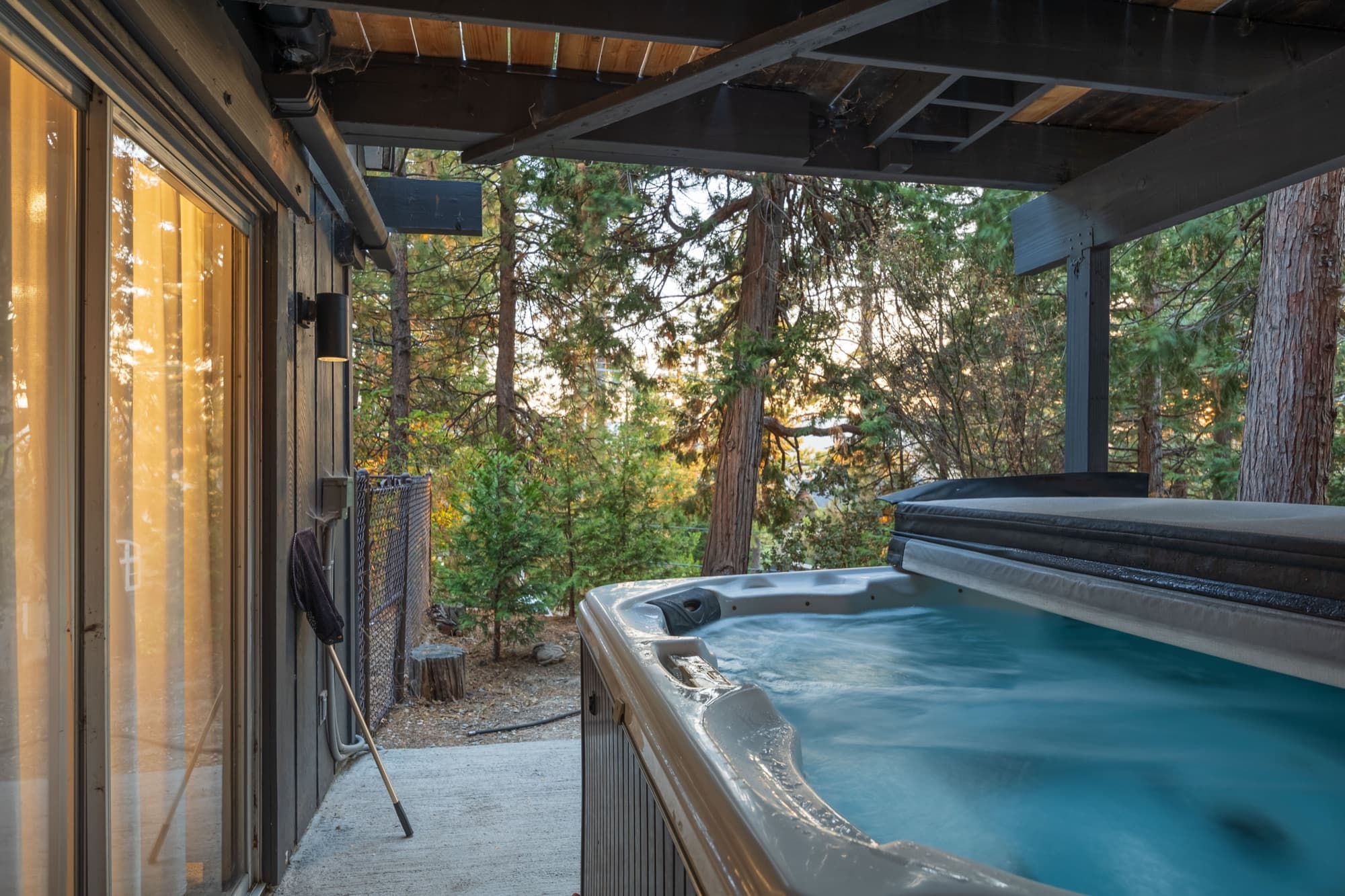 Hot tub on lower deck surrounded by towering pine trees at golden hour